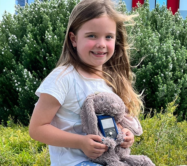 Girl holding a teddy bear with an insulin pump